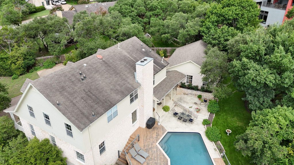 Rear of a two-story home in Lost Creek, Austin 78746, showing the worn original roof before replacement