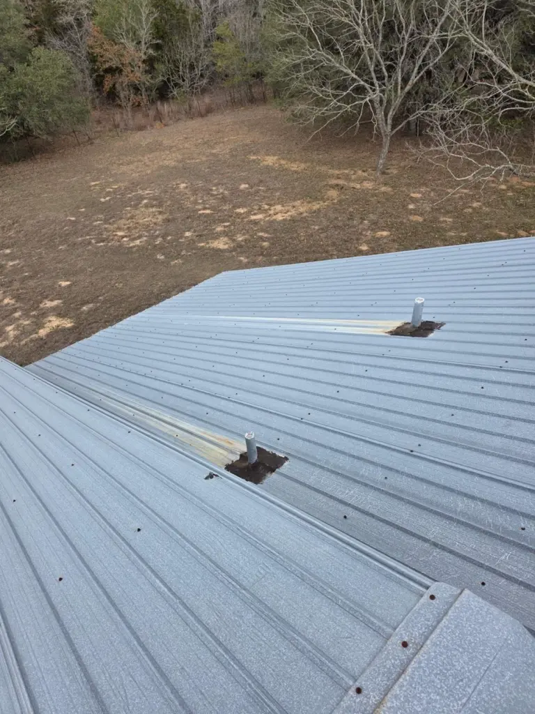 Rust streaks below pipe penetrations on the old exposed-fastener roof