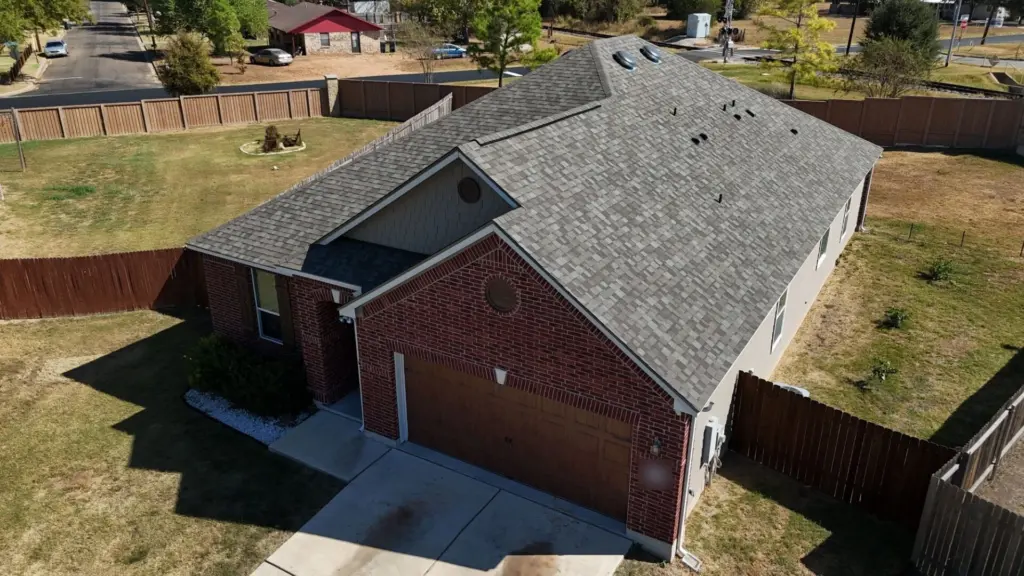 Aerial view of a one-story red brick home in Bastrop with a new Owens Corning Duration roof in Driftwood