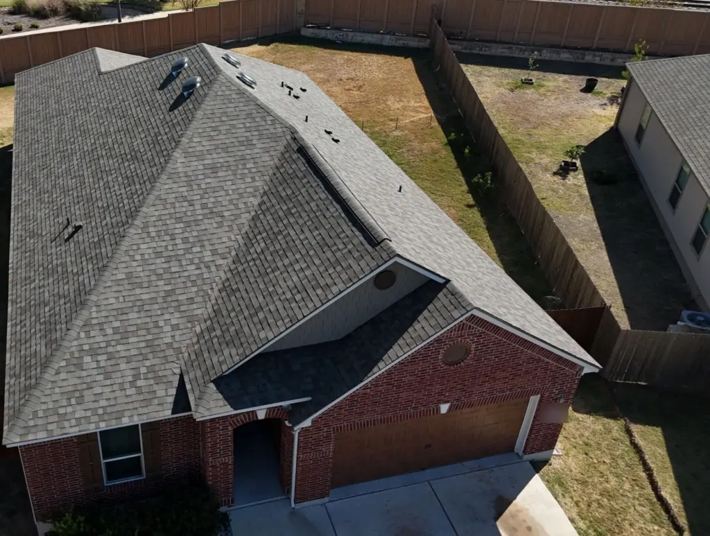 Overhead view of the new roof showing the ridge vent over the garage and four dome vents near the main roof's peak