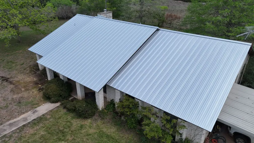 Standing seam metal roof on a one-story stone house on Glass Lane in Bastrop, TX