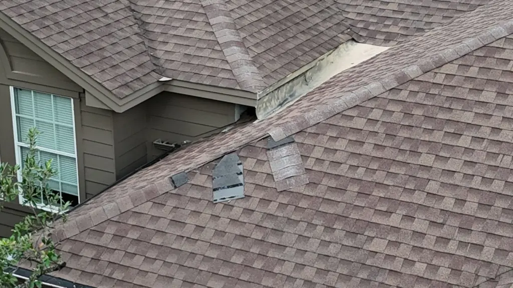 Missing ridge cap and torn, loose shingles on a 20-year-old roof in West Lake Hills before replacement