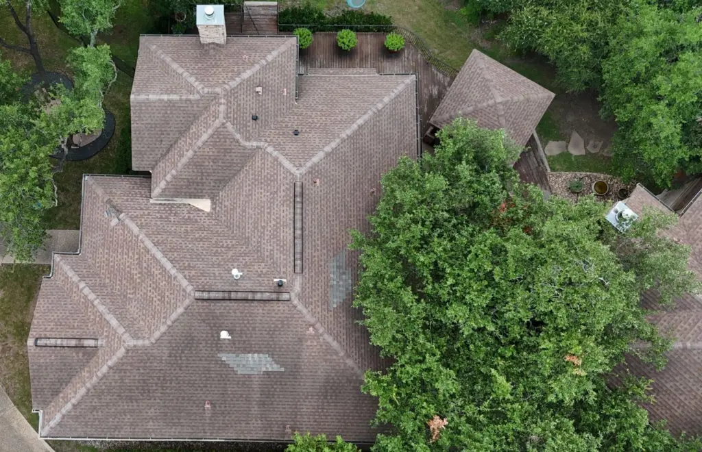 Overhead drone view of the old roof in West Lake Hills showing short ridge vent sections and mismatched shingle patches