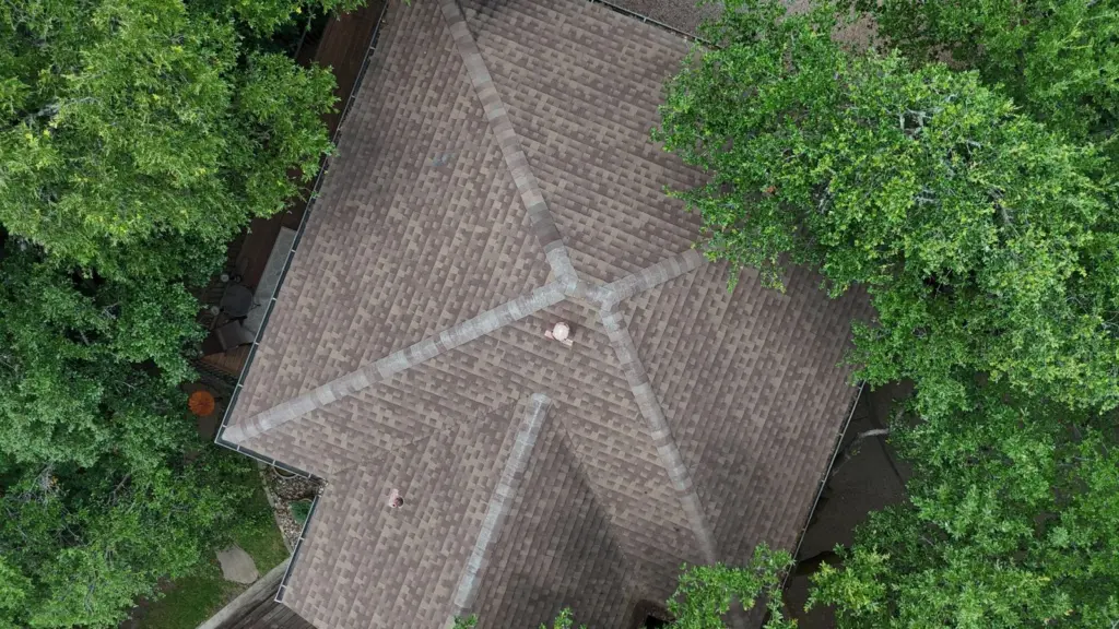 Overhead view of worn ridge caps on a hip roof section before replacement